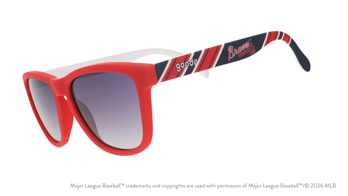 Three-quarter angle view of red, white, and navy Braves sunglasses featuring the script and tomahawk logo on the arm.