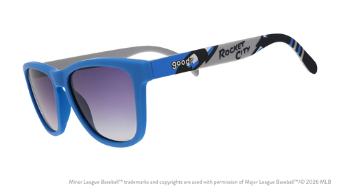 Three-quarter angle view of sunglasses tilted down. Blue frames w/ Rocket City on temples + black gradient lenses.