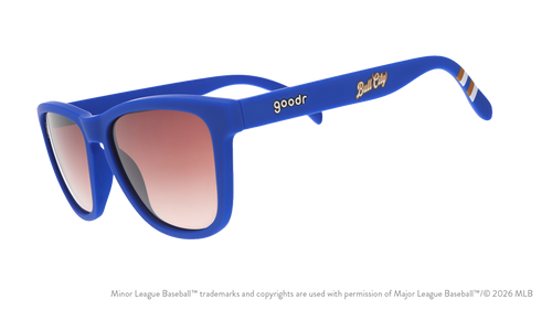 Three-quarter angle view of shades. Blue frames w/ stripe pattern+Bull City on temples. Brown gradient lenses.