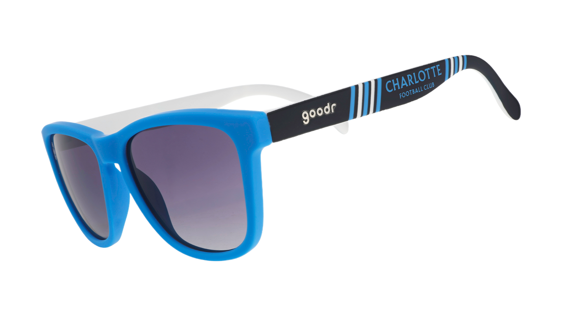 Three-quarter angle view of MLS Charlotte FC shades tilted down. Blue+black frames. Black gradient lenses.