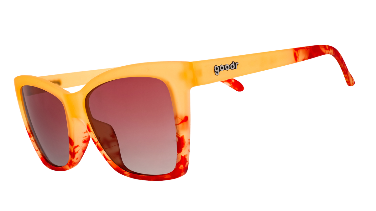 Three-quarter angle view of translucent yellow-orange sunglasses with red hand-painted whirls & rose ocean gradient lenses.