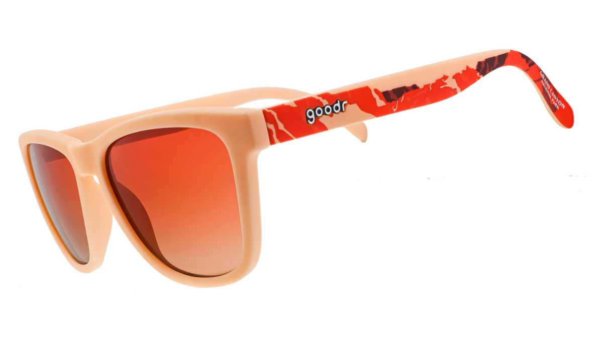 Grand Canyon National Park sunglasses, featuring square frames, orange lenses, and a mountain silhouette design across the temples in shades of orange, brown, and peach.