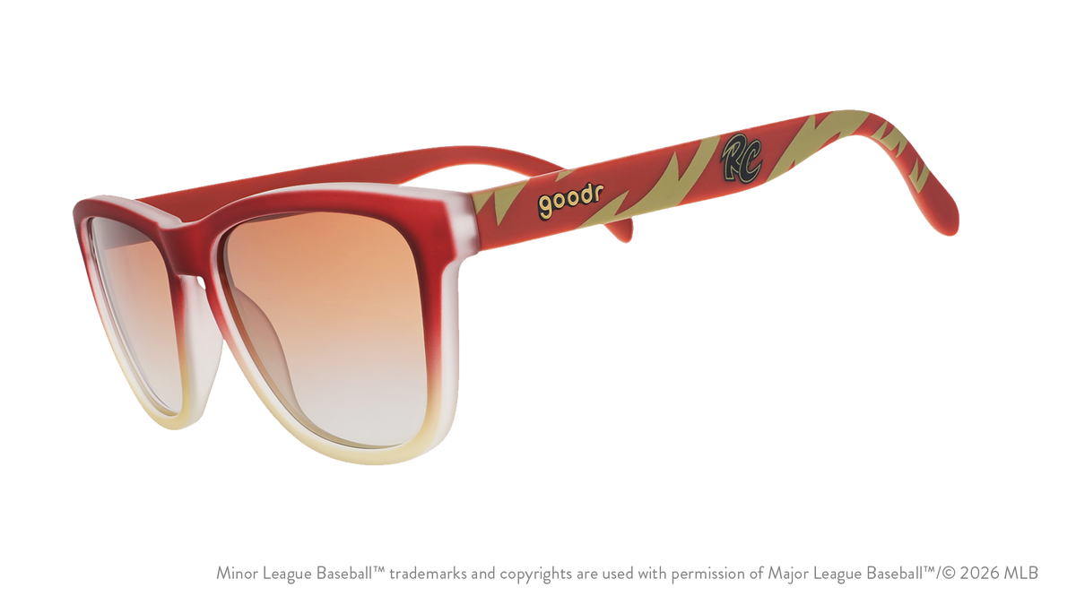 Three-quarter angle view of sunglasses tilted down. Brown + red frames w/ RC on temples + amber gradient lenses.