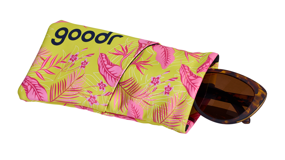 Three-quarter angle view of a soft fabric sunglasses case featuring a tropical design. A pair of tortoiseshell shades is shown partially pulled out.