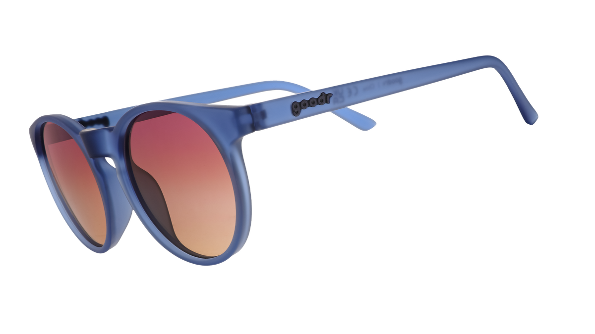 Three-quarter angle view of dark blue circular sunglasses with purple-yellow ocean lenses.