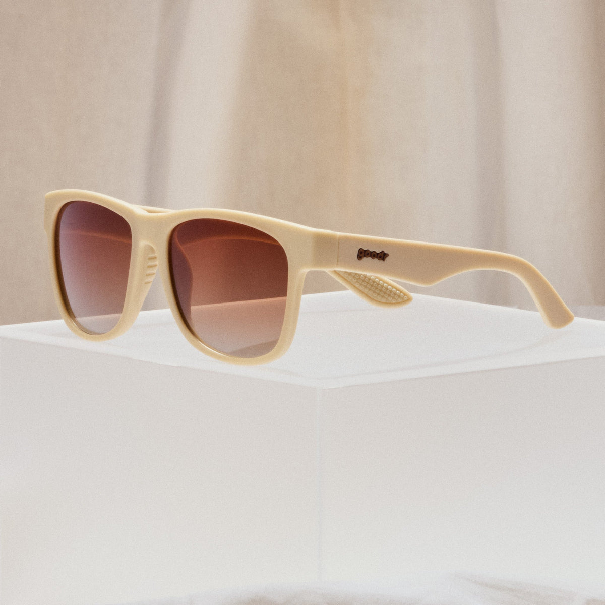 A pair of square sunglasses with tan frames and burnt orange lenses.