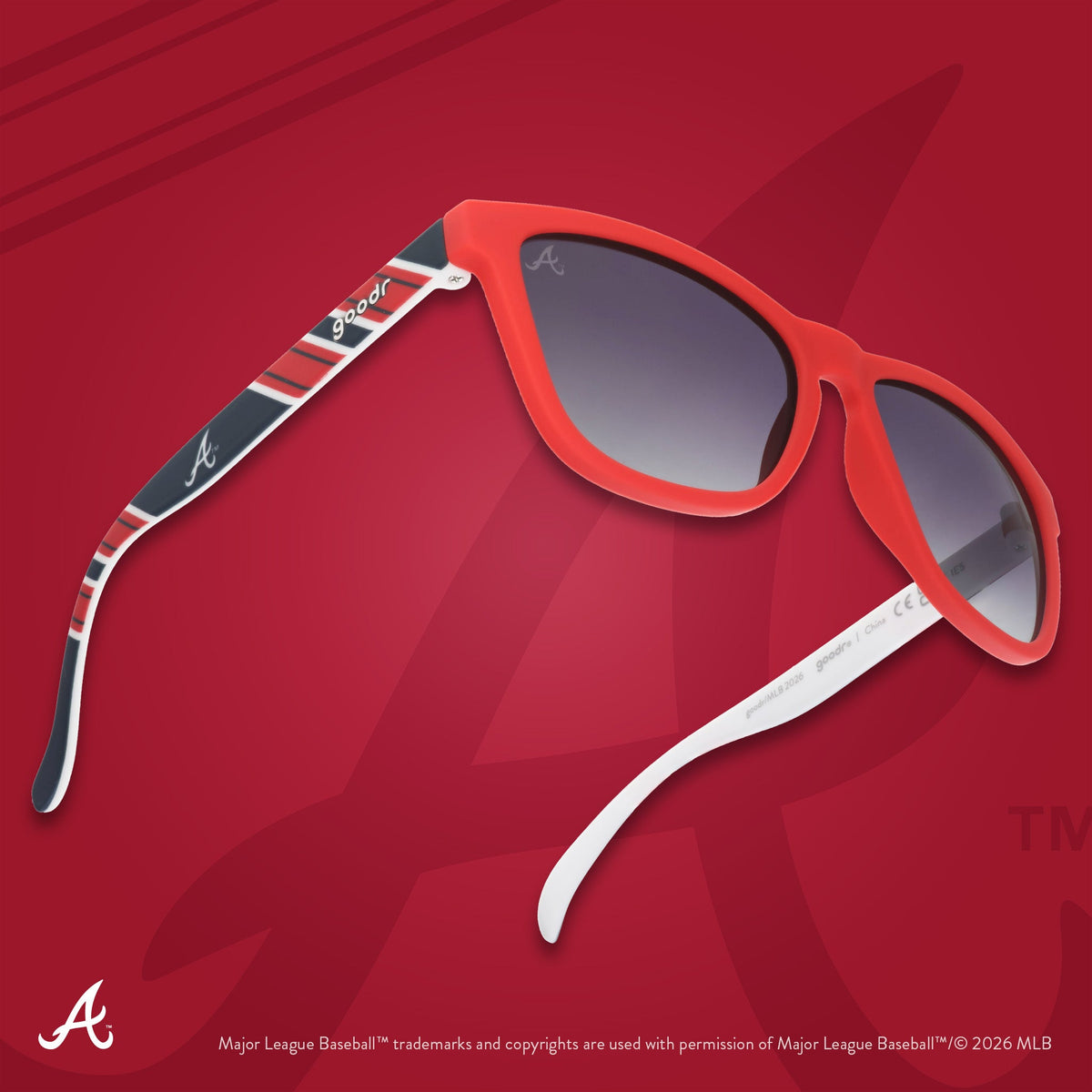 Three-quarter angle view of a pair of red, white, and navy Braves sunnies floating against a red background featuring the A.