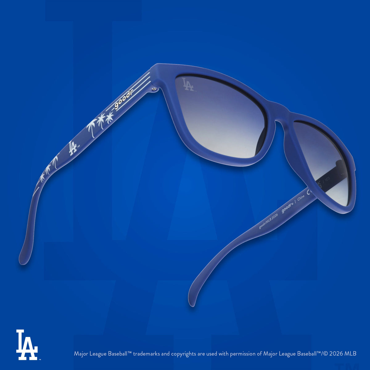 Three-quarter angle view of a pair of blue and white sunglasses featuring the Dodgers' LA logo and palm trees on the arm.